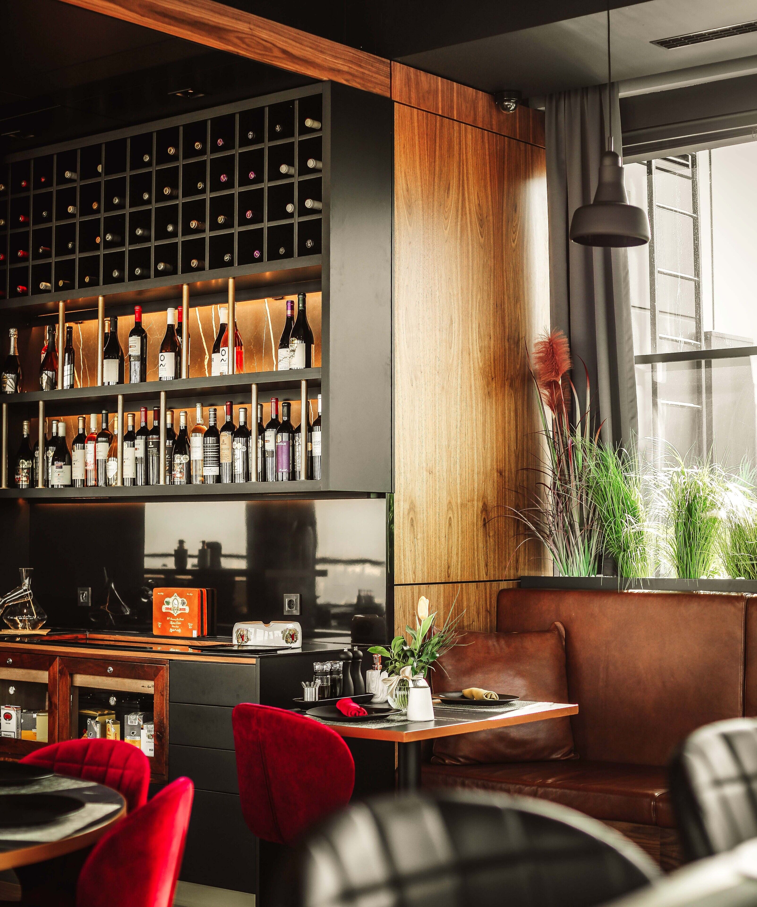 Un'area bar moderna con un portavino, sedute in pelle e un'ampia finestra.