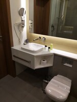 Un baño moderno con un lavamanos blanco, un inodoro y un espejo.