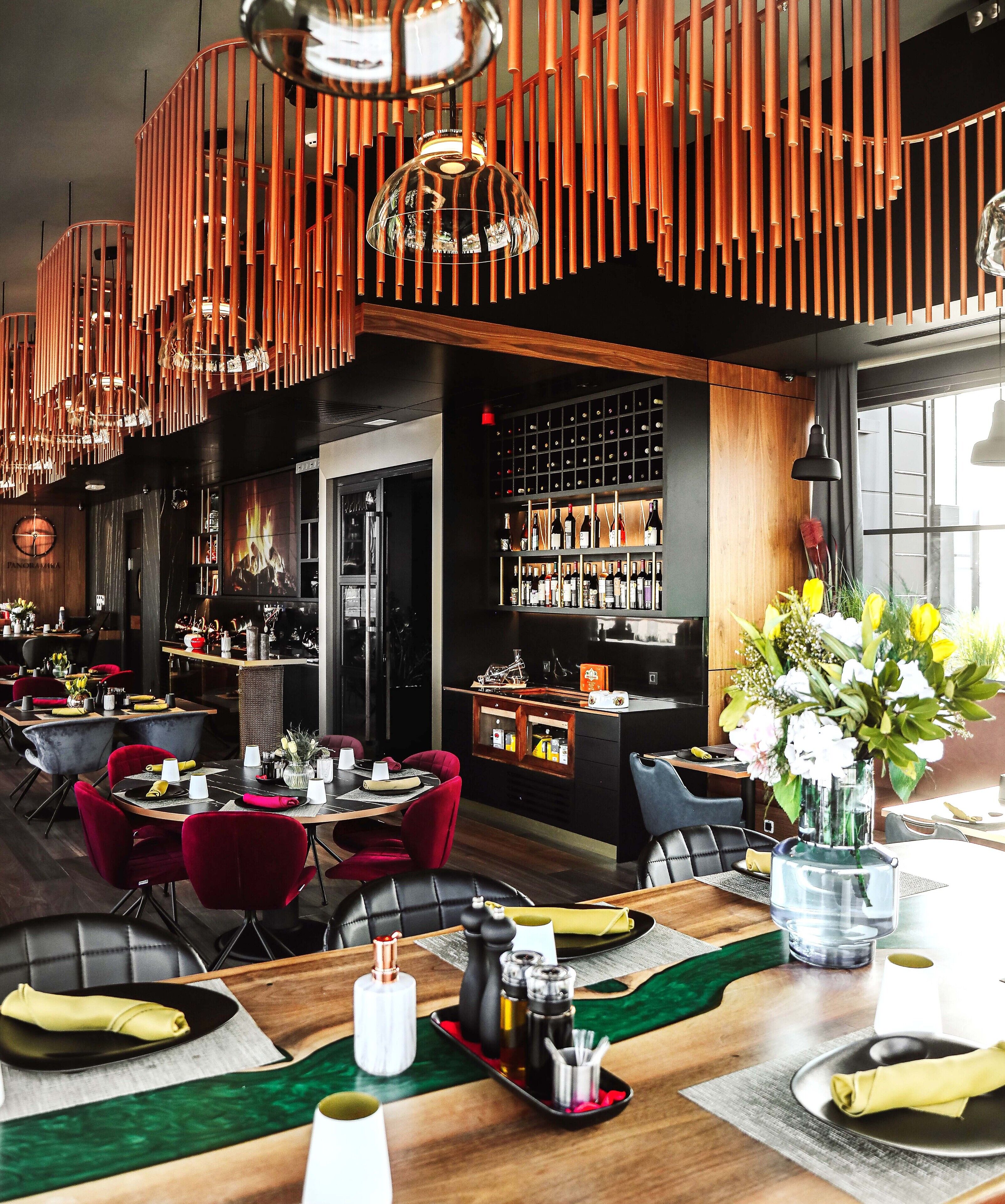 A restaurant with a modern interior, featuring wooden tables, red chairs, and a variety of dining options.