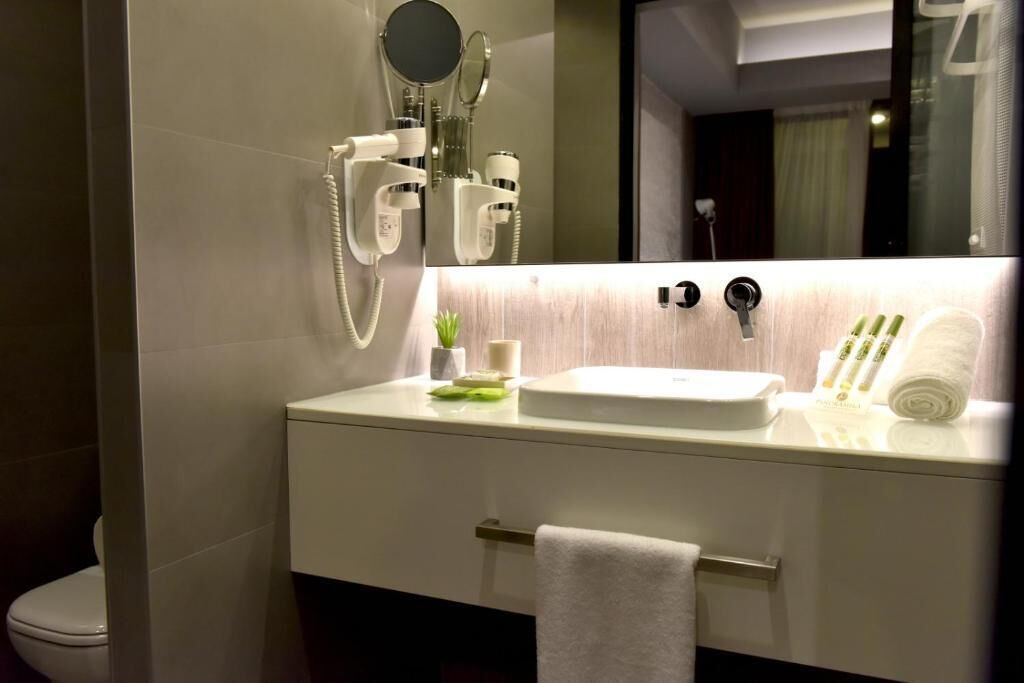 Un baño moderno con un lavamanos blanco, un espejo y un perchero para toallas.