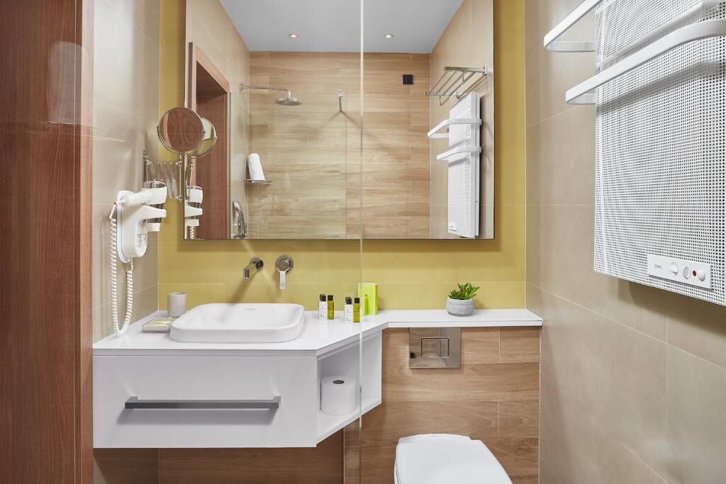 Een moderne badkamer met een wit aanrichtmeubel, een spiegel, een douche en een handdoekhouder.