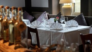 A restaurant setting with a table set for dining, including wine bottles, glasses, and a lamp. - Hotel Brunnenhof International (Wedemark)