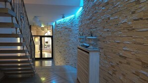 Un interior moderno con una escalera, una pared de piedra y una recepción.