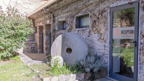 A stone building with a reception area, a stone well, and a garden with various plants. - Agriturismo La Petrosa (Ceraso)