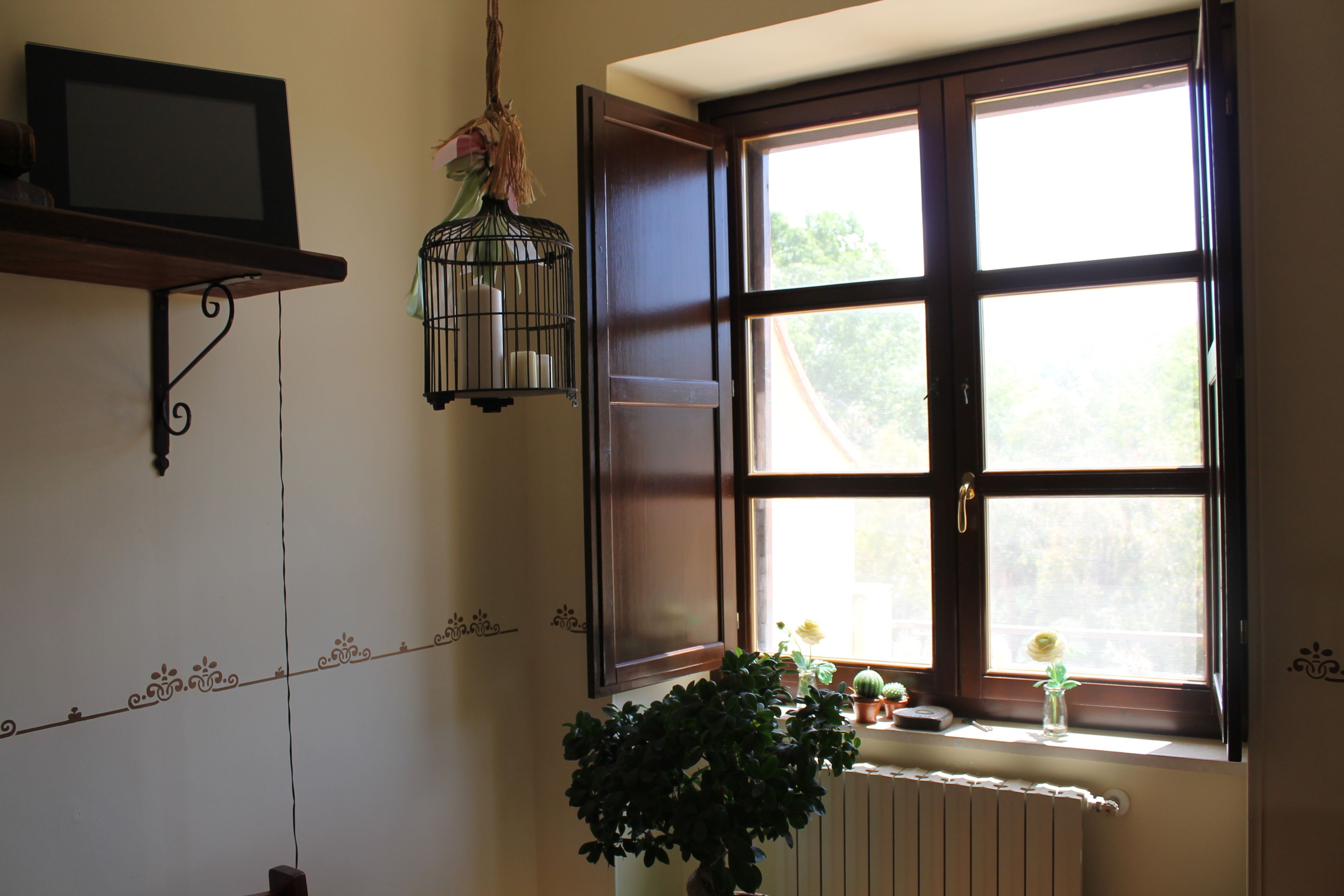 Une pièce avec une grande fenêtre, un radiateur et une plante en pot.
