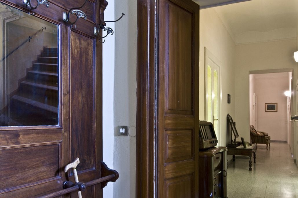 A wooden staircase leading to a landing with a vintage television set and a chair.
