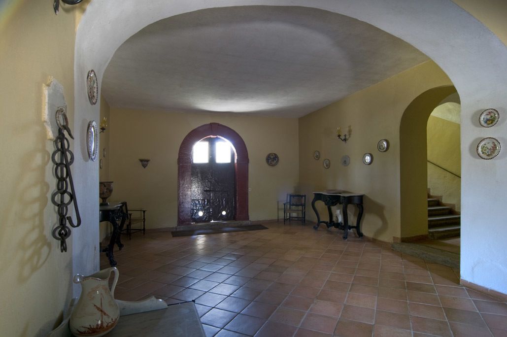 Un intérieur doté d’un sol carrelé, d’une arche centrale et d’un escalier menant à un autre niveau.