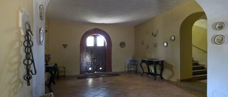 An interior with a tiled floor, a central archway, and a staircase leading to another level.