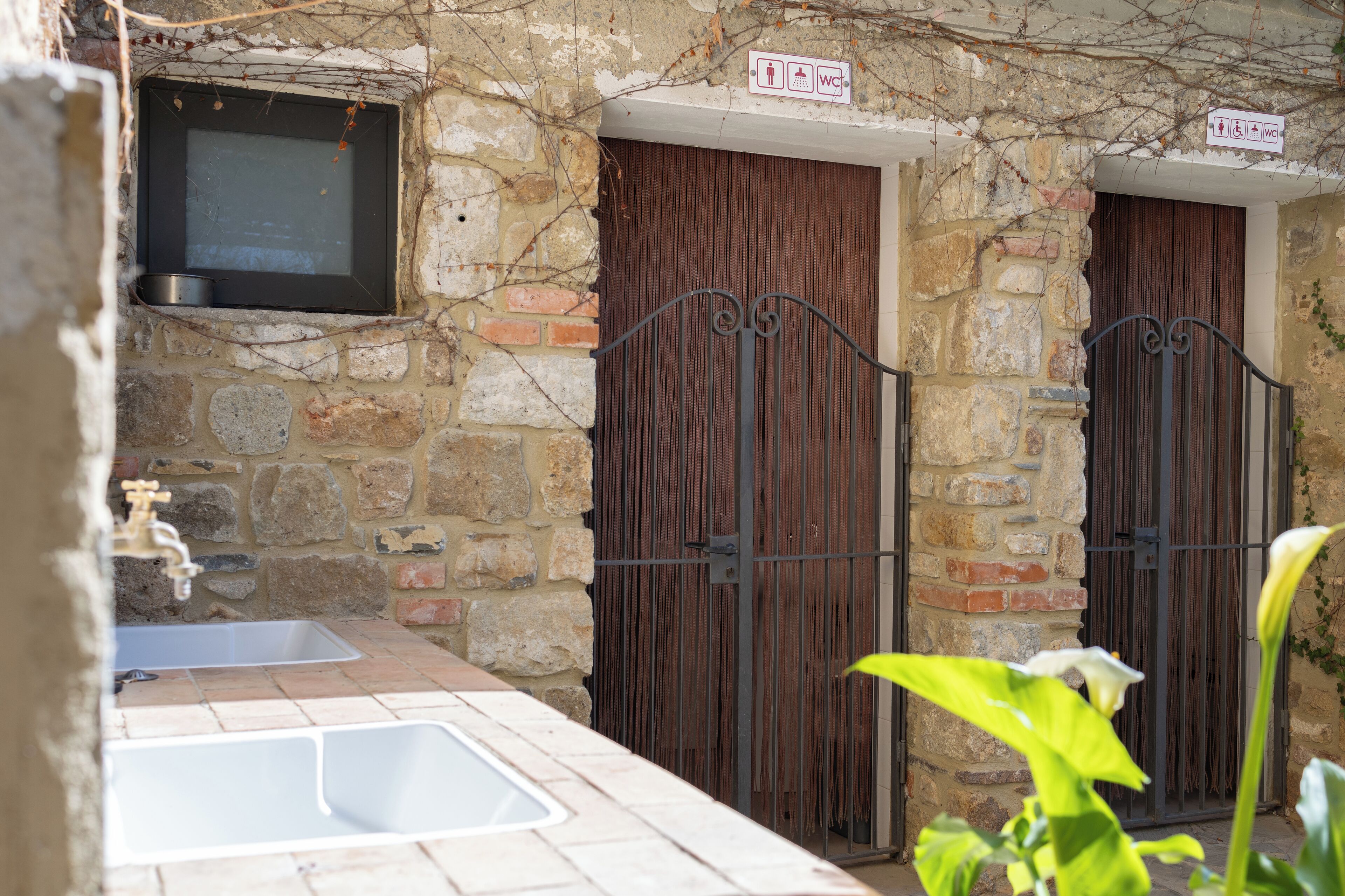 Un bâtiment en pierre avec une porte en métal, un évier et une fenêtre.