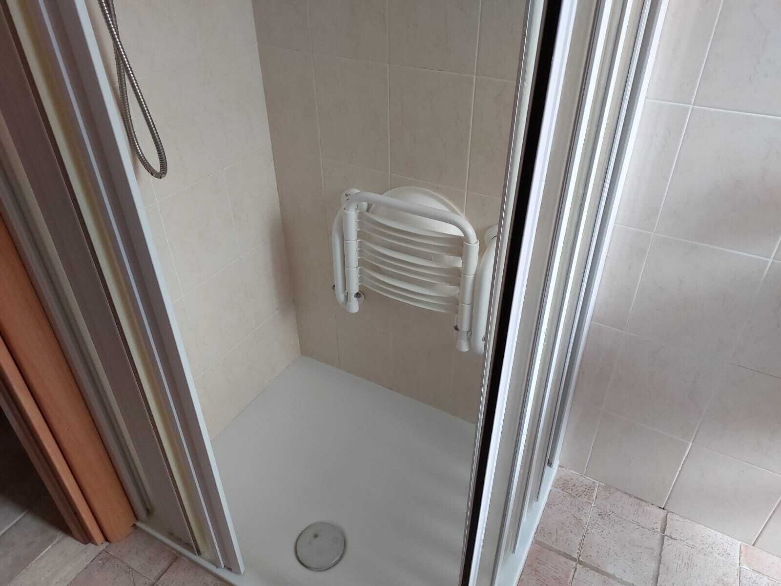 A shower area with a glass door, a white towel rack, and a drain on the floor.