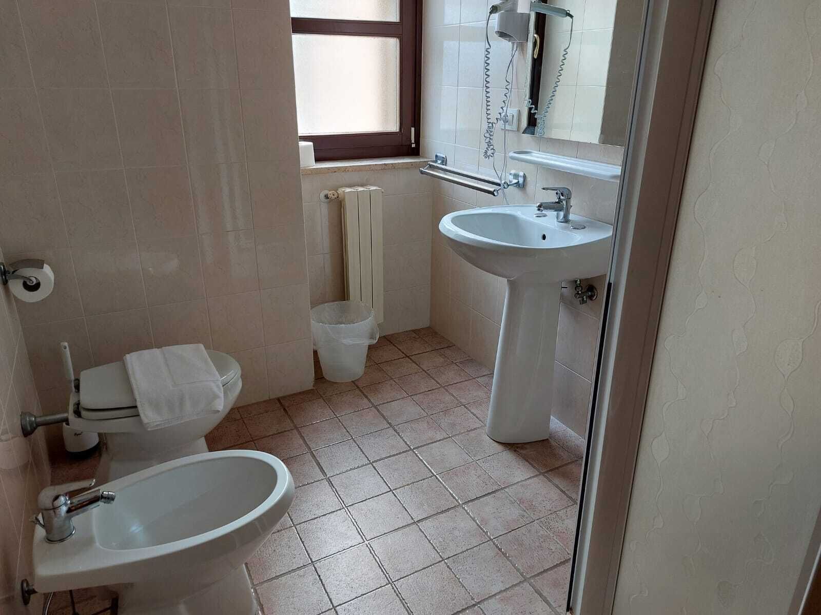 Un bagno con il water, un bidet, un lavandino e una finestra.