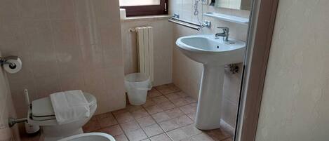 Un bagno con il water, un bidet, un lavandino e una finestra.