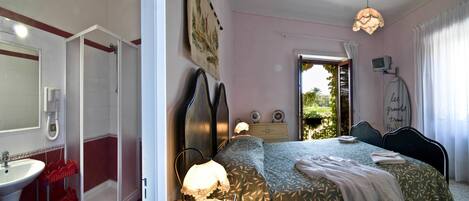 Un dormitorio con cama, mesita de noche, lámpara y vistas al exterior.
