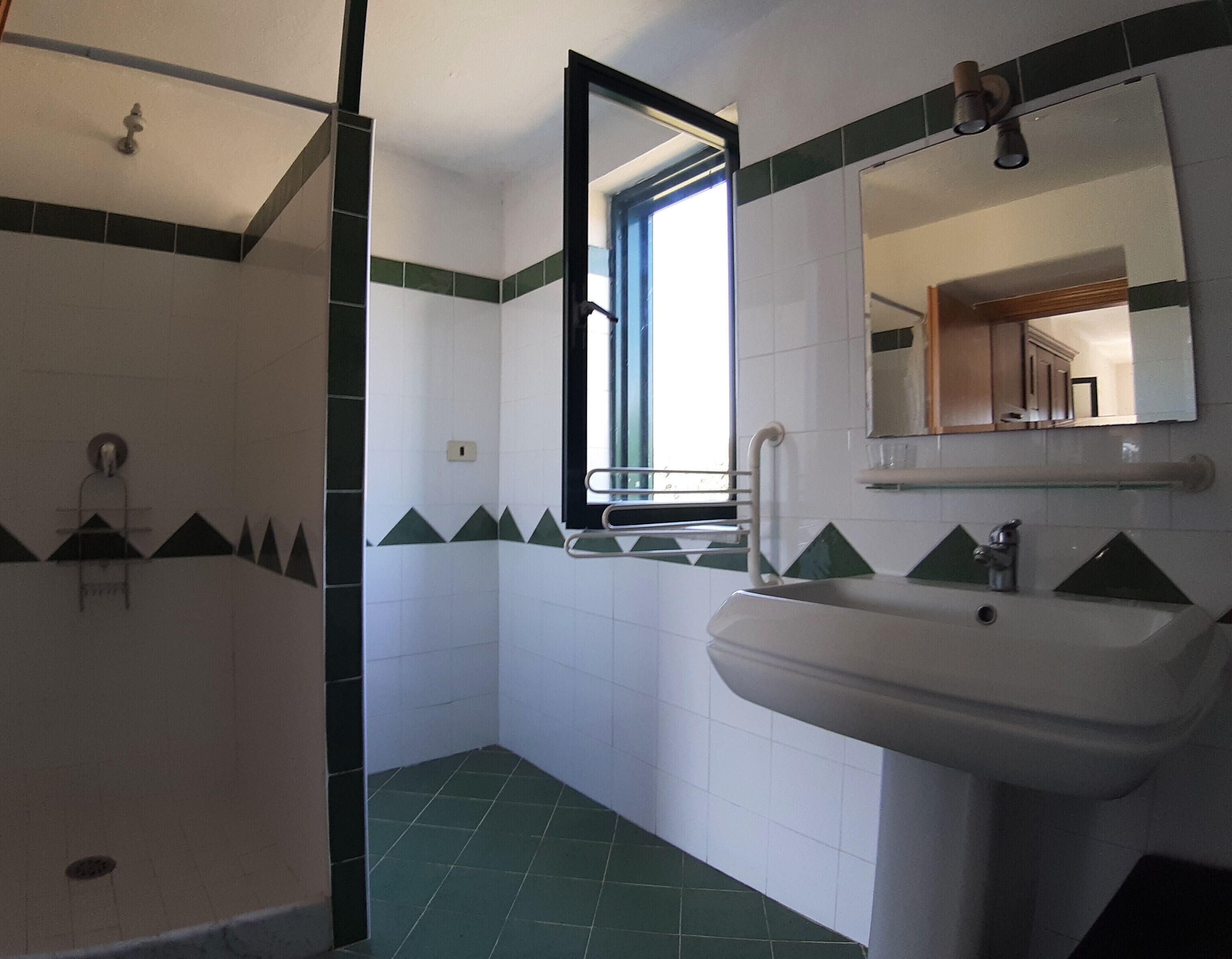 Baño con ducha, lavamanos y ventana.