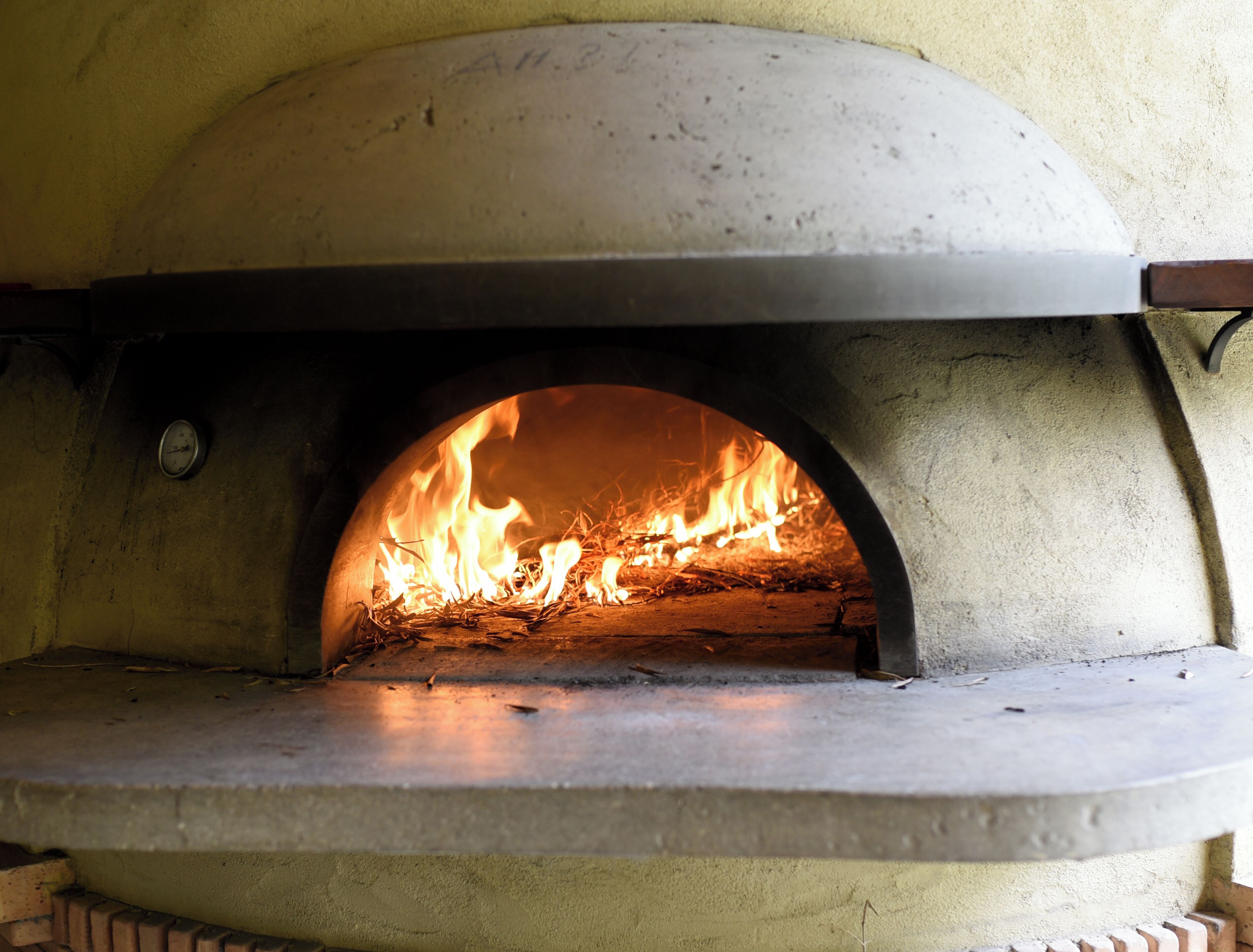 Un four en briques dans lequel on allume un feu, probablement utilisé pour la cuisson des aliments.