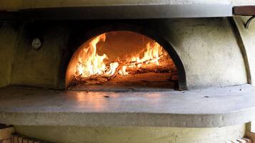Un four en briques dans lequel on allume un feu, probablement utilisé pour la cuisson des aliments.