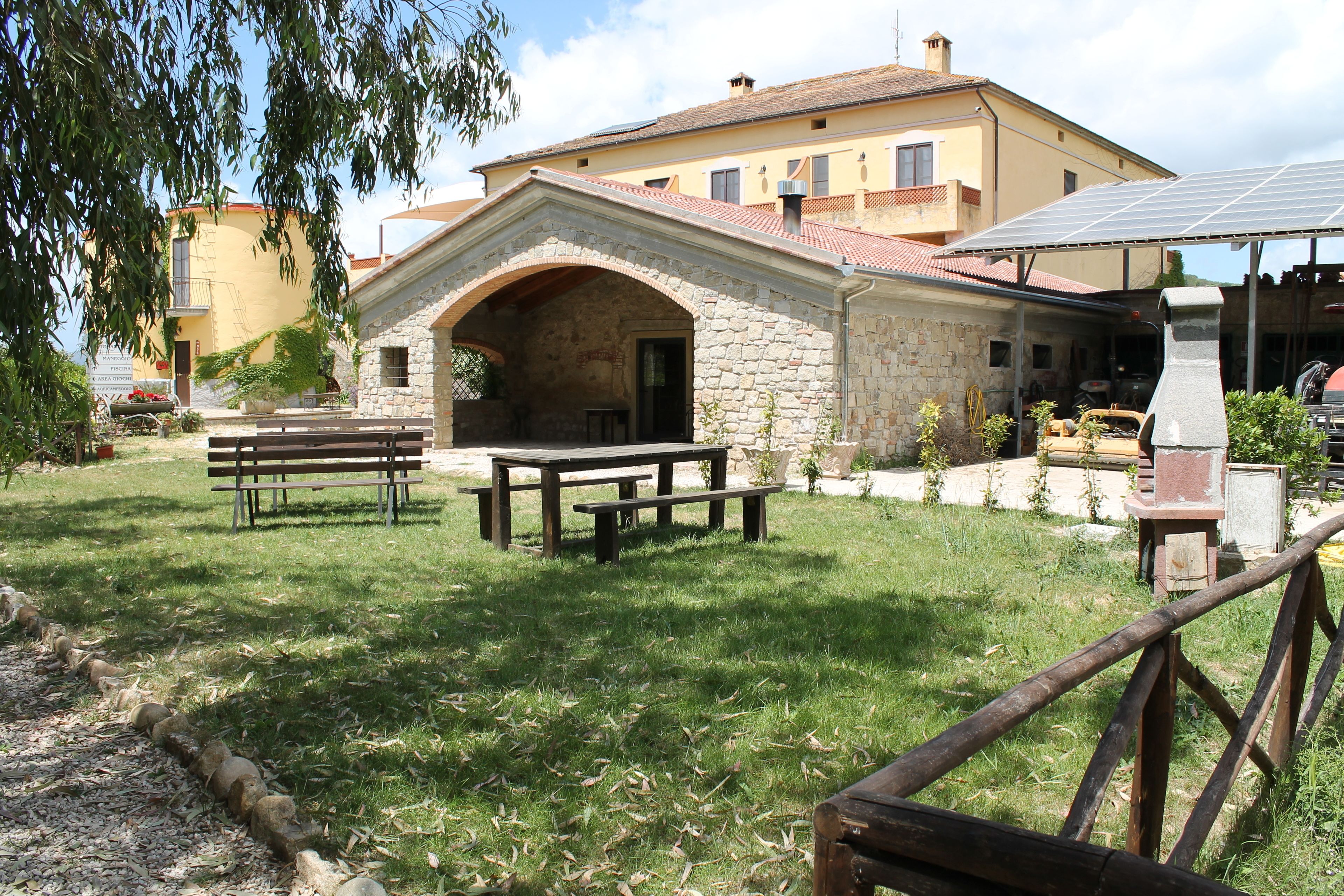 A stone building with a covered patio area, picnic tables, and a barbecue setup.
