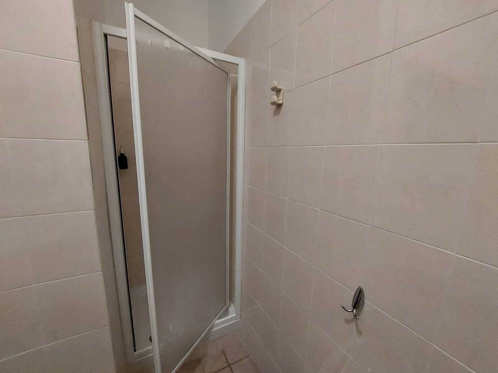 Un baño con paredes de baldosas color beige, una puerta blanca y un perchero.