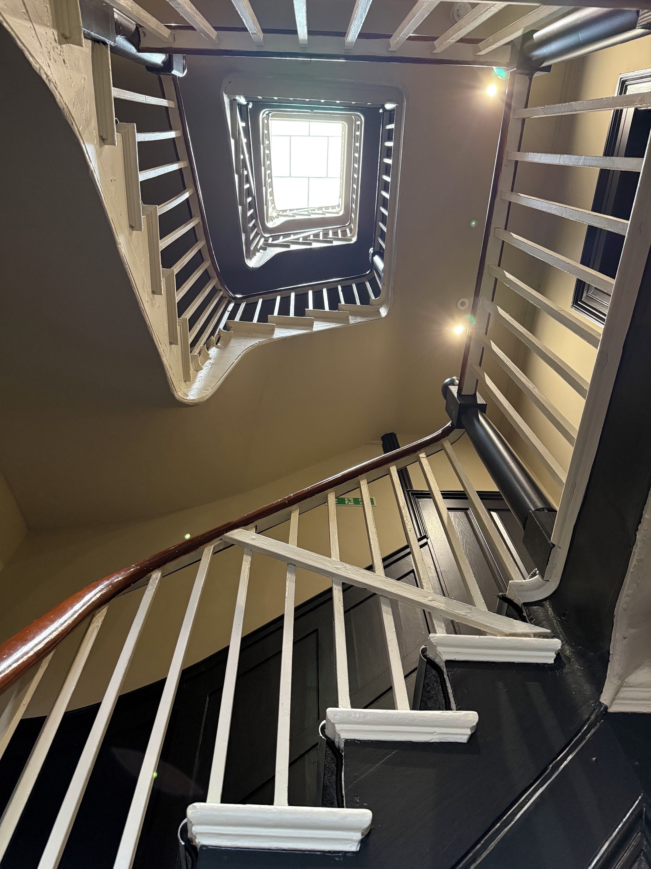 Una escalera con barandilla, suelo negro y una lámpara colgante.