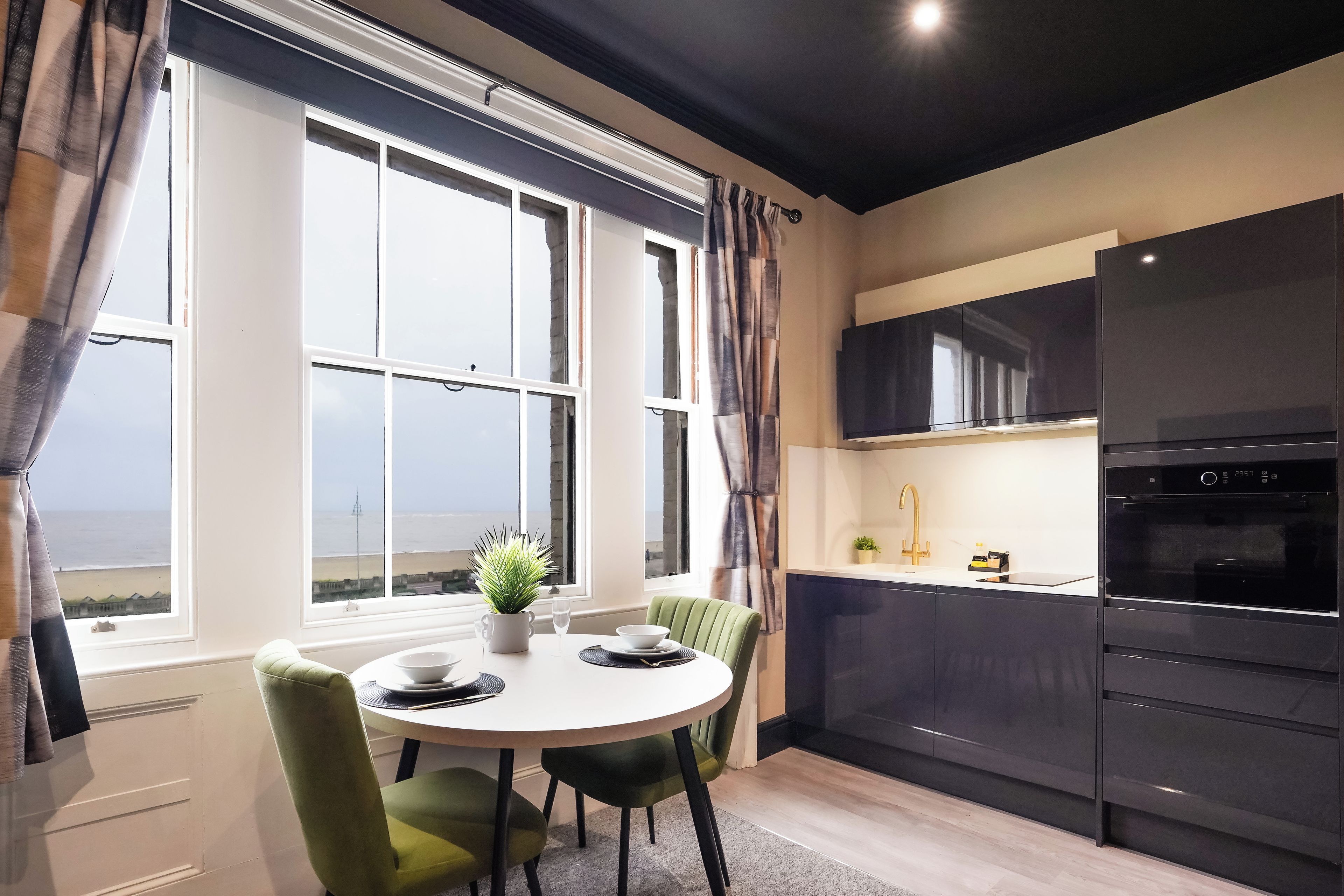 A modern kitchen with a built-in oven and a dining area with a view of the sea.