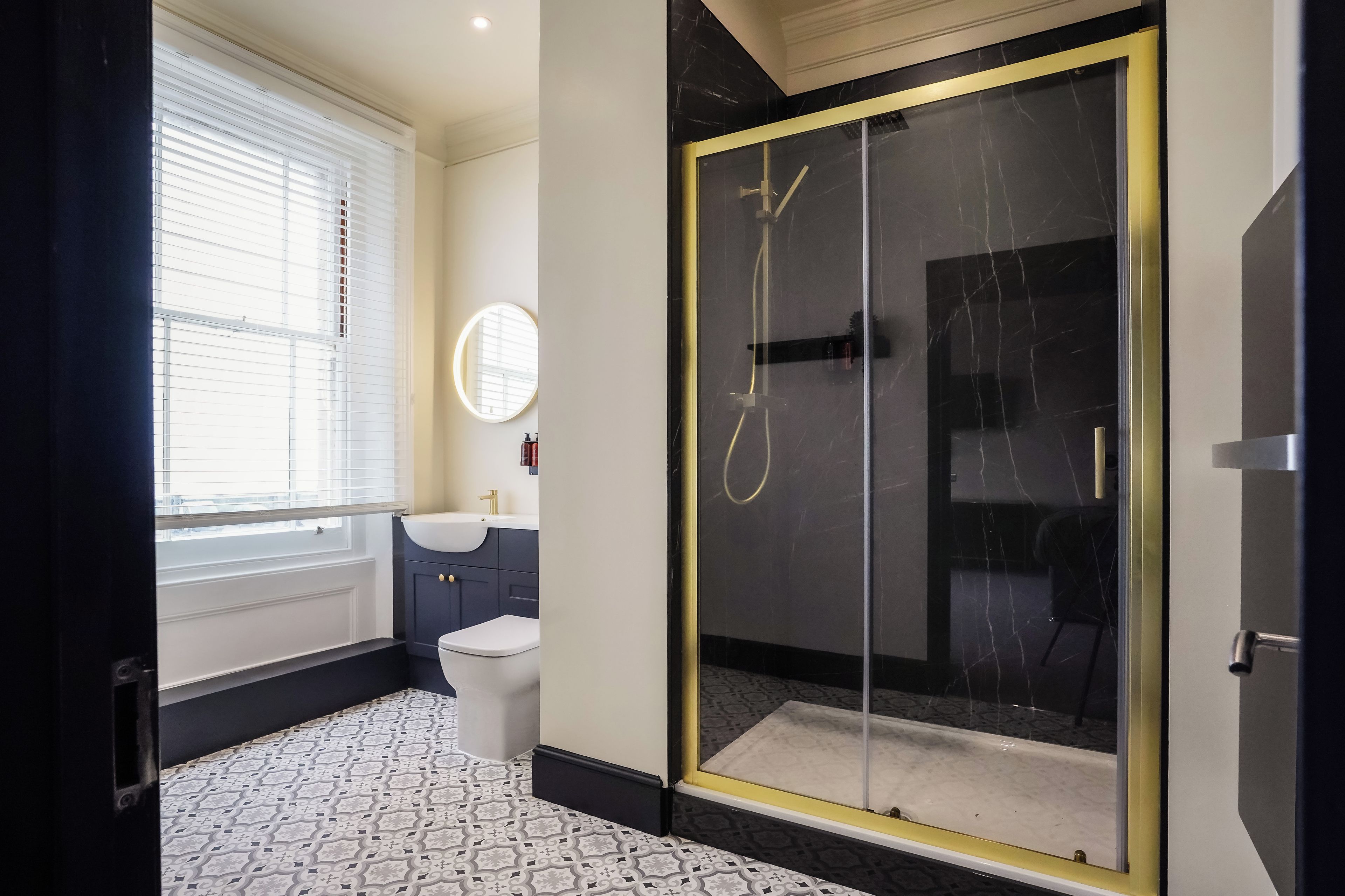Un baño moderno con inodoro, lavamanos y ducha con mampara de vidrio.