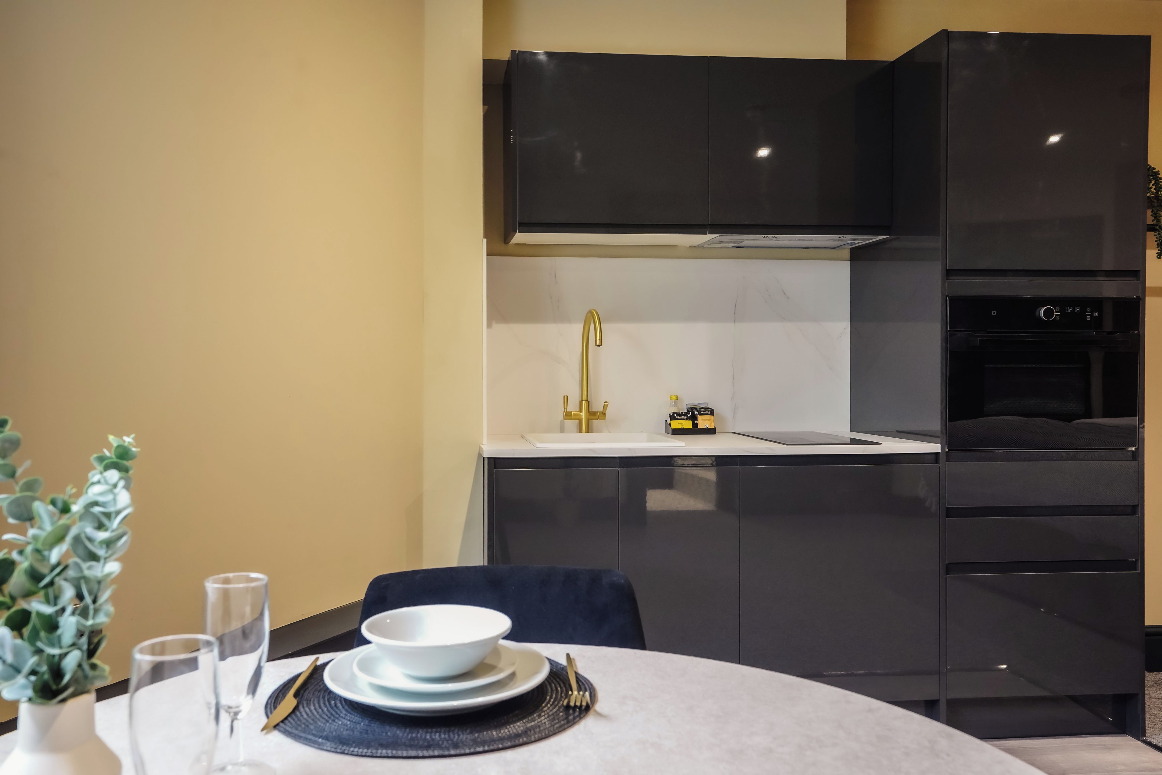 A modern kitchen with black cabinetry, a white countertop, and a built-in oven.
