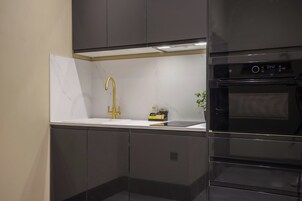 Una cocina moderna con horno empotrado, campana de acero inoxidable y grifo dorado.