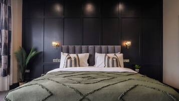A modern bedroom with a dark wood panel wall, a tufted headboard, and two wall-mounted light fixtures.
