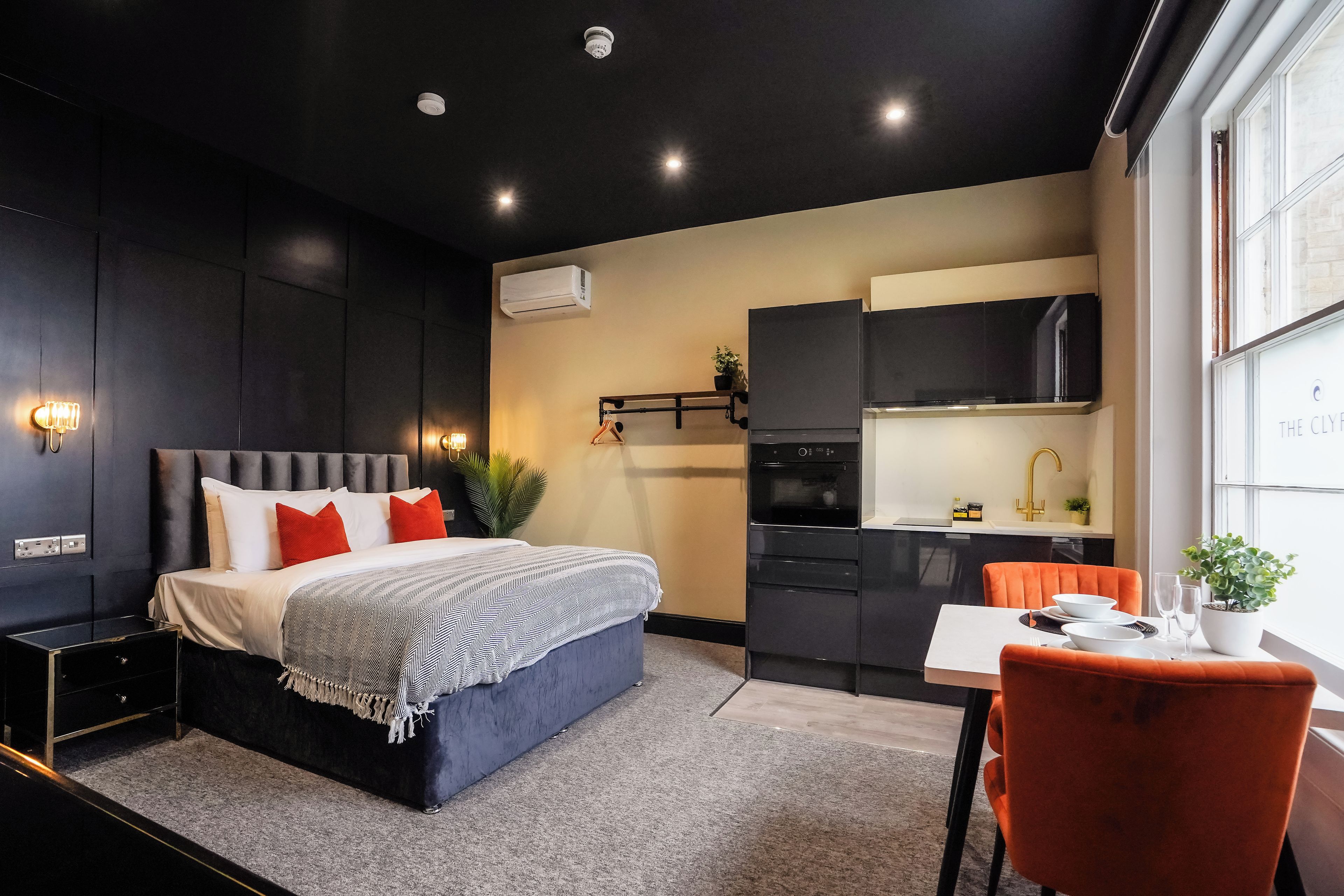 A modern bedroom with a bed, bedside table, and a small desk area.