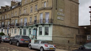 Un edificio histórico con un letrero que dice "The Clyffe Hotel". Presenta un estilo arquitectónico clásico con múltiples ventanas y balcones.