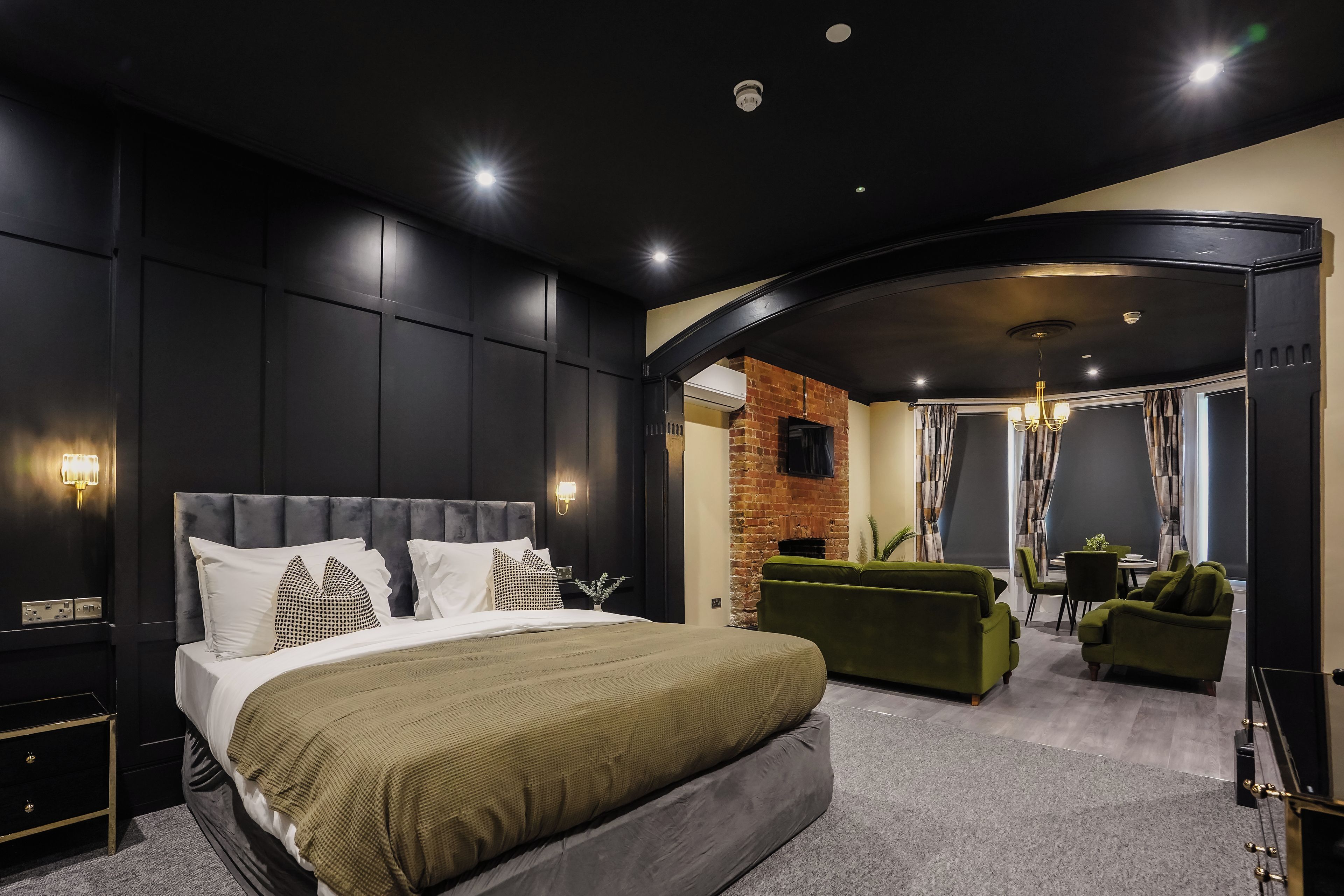 Un dormitorio moderno con una cama grande, un sofá verde y una zona de comedor con mesa y sillas.