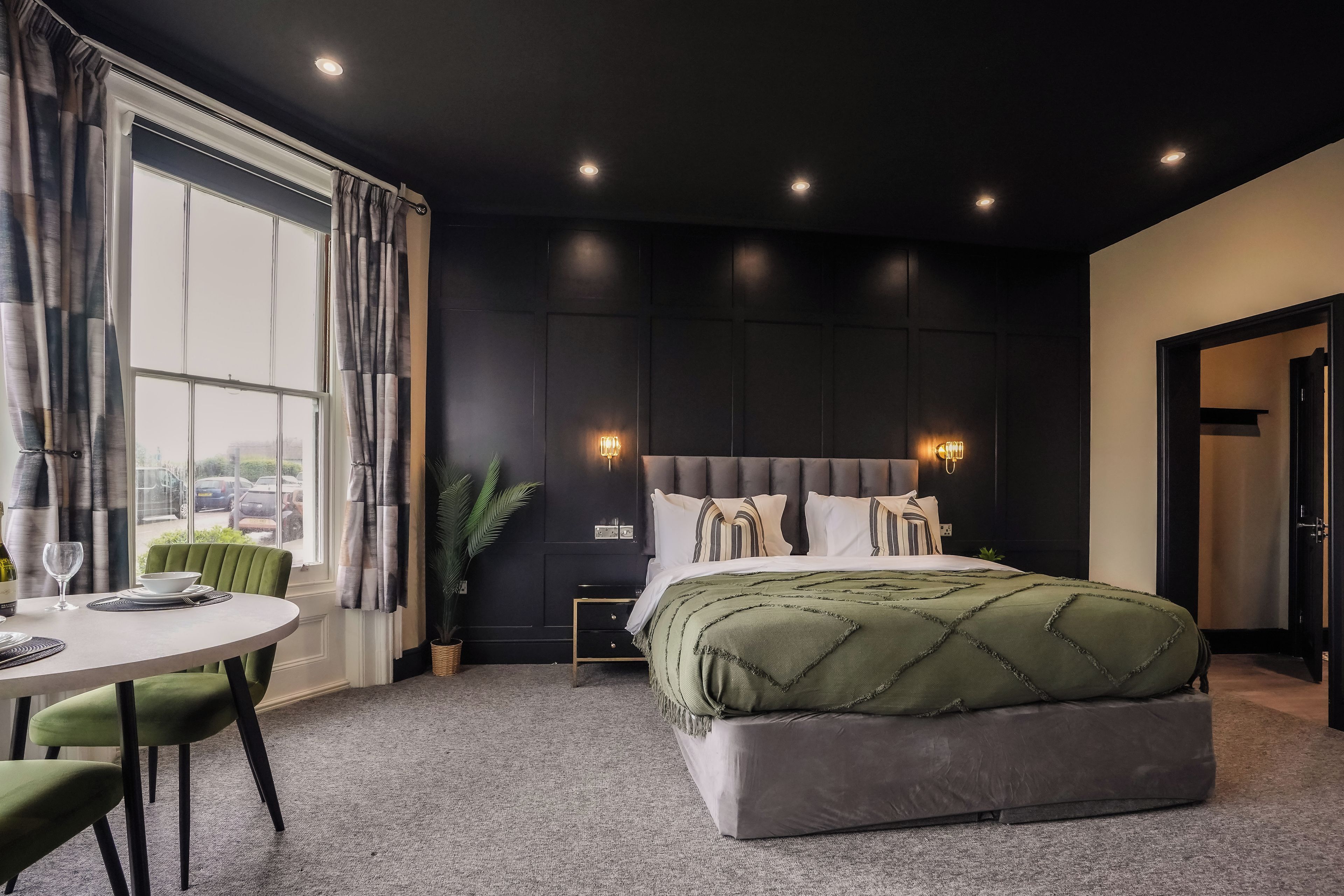 Un dormitorio moderno con una cama grande, una mesita de noche, una ventana con cortinas y vistas al exterior.