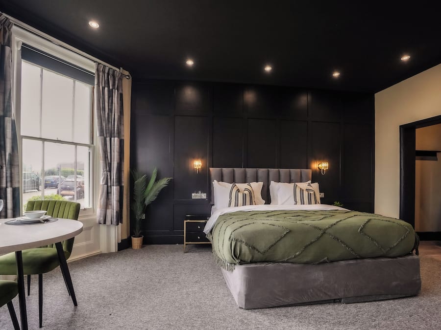Un dormitorio moderno con una cama grande, una mesita de noche, una ventana con cortinas y vistas al exterior.