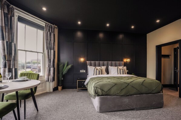 Un dormitorio moderno con una cama grande, una mesita de noche, una ventana con cortinas y vistas al exterior.