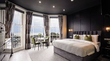 A modern bedroom with a large bed, a dining table, and a view of the city.