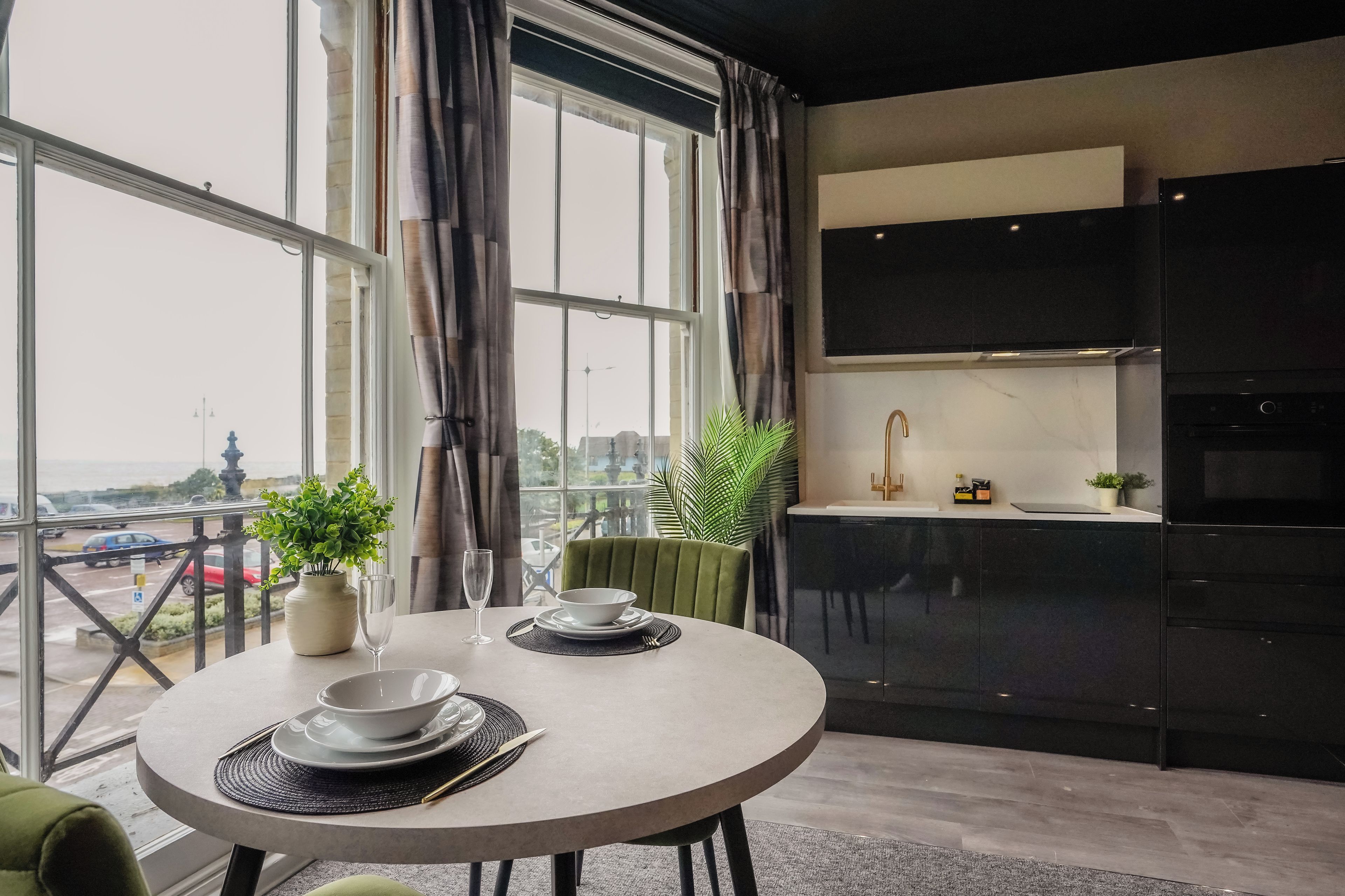 A modern dining area with a round table, chairs, and a view of the city through large windows.
