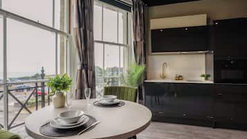 A modern dining area with a round table, chairs, and a view of the city through large windows.