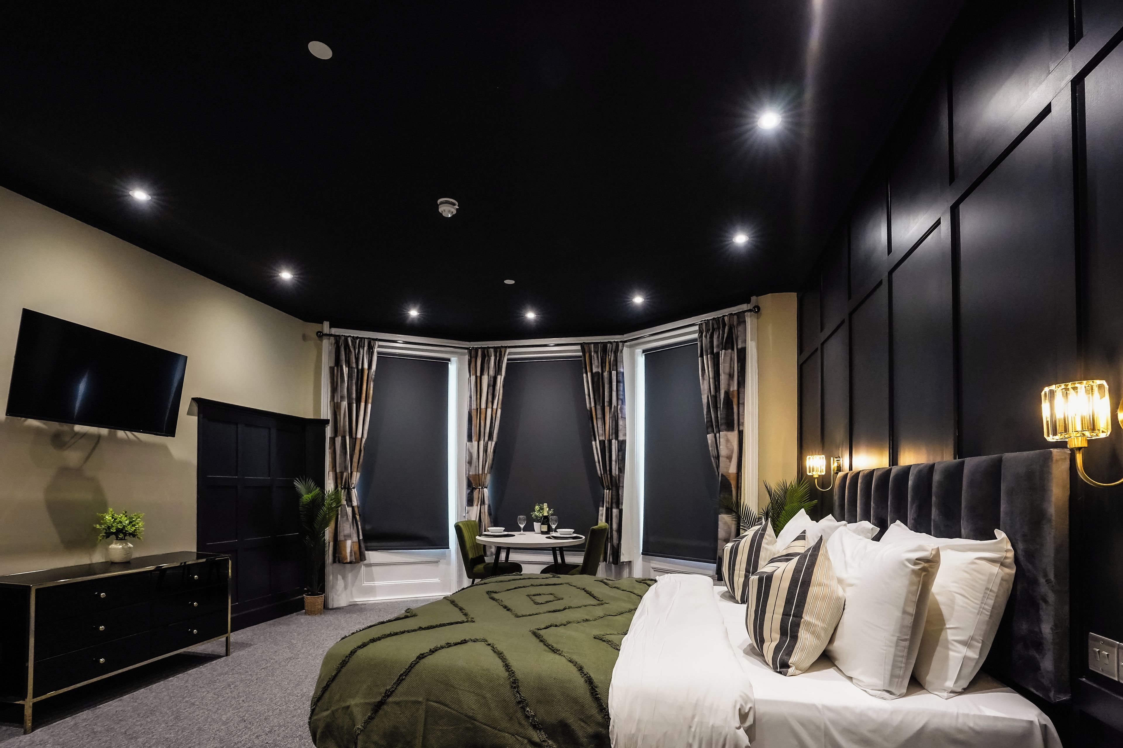 A modern bedroom with a bed, a TV, a desk, and a chair.