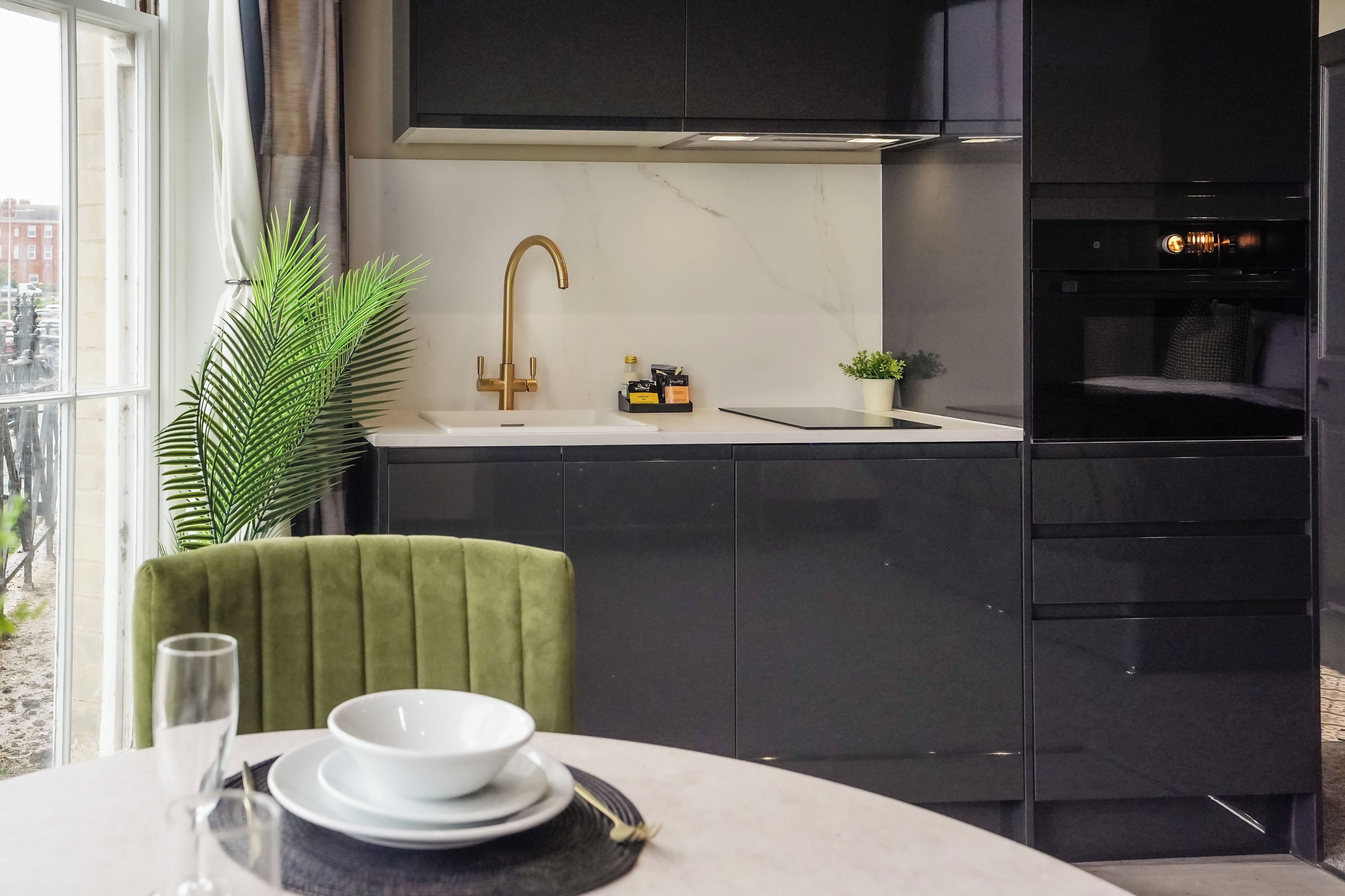 Una cocina moderna con encimera de mármol, grifo dorado y horno negro.