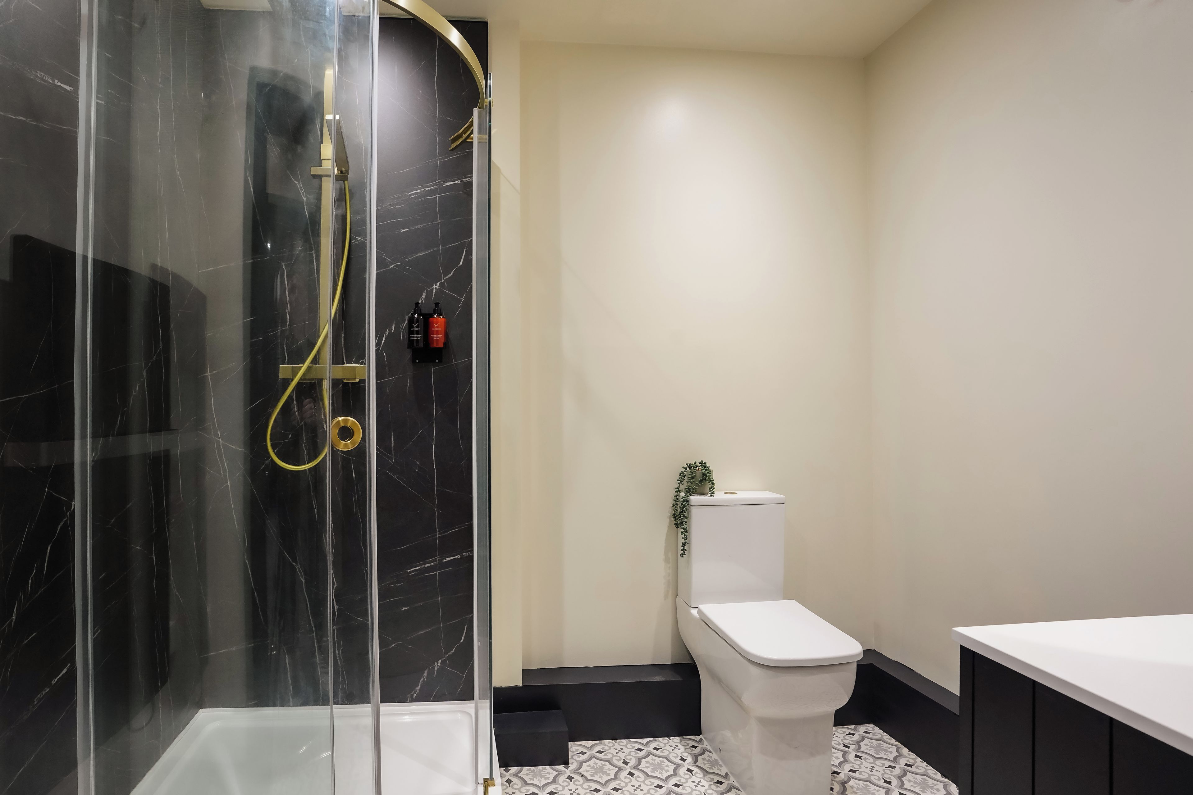 A modern bathroom with a glass-enclosed shower, a toilet, and a sink.