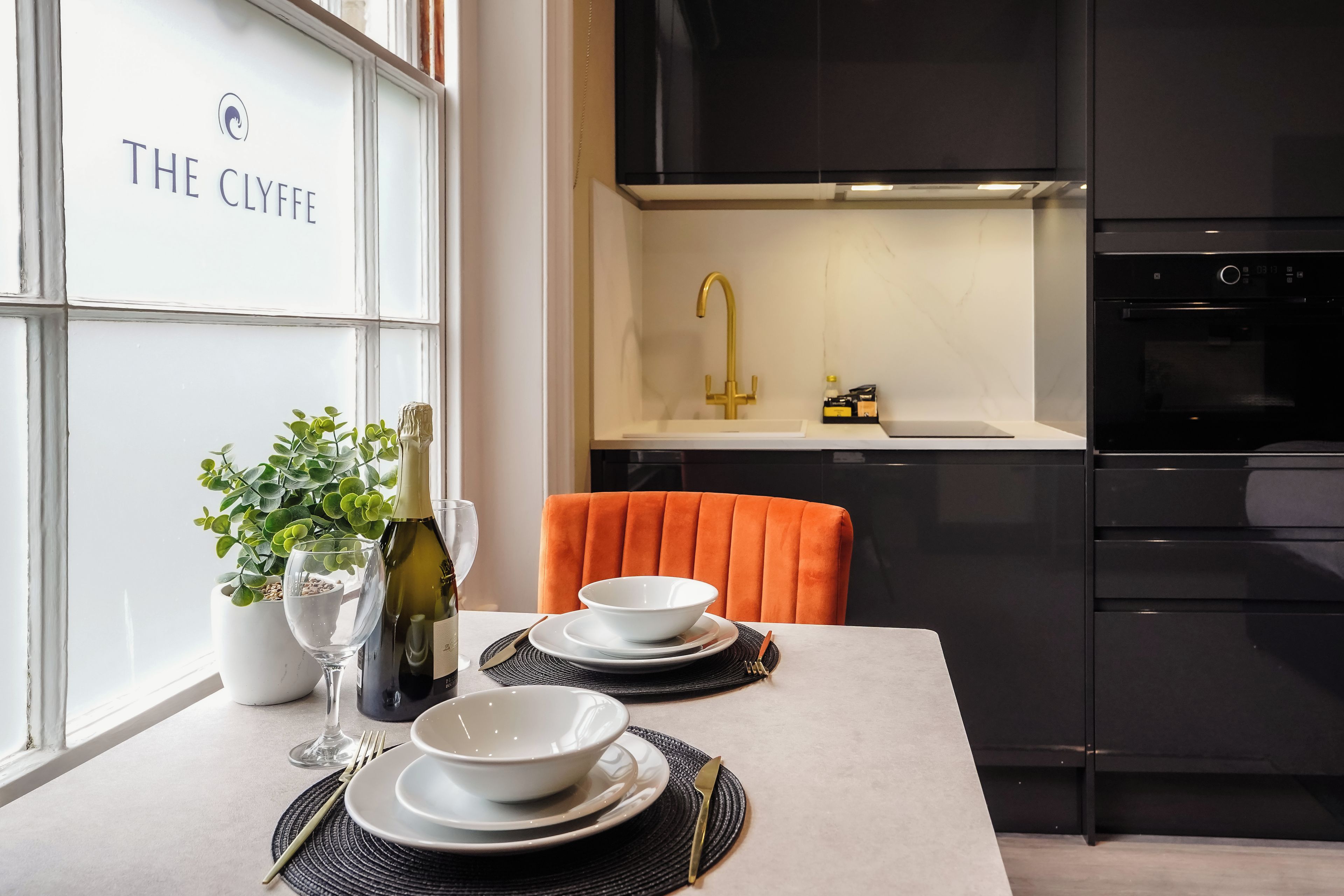 A modern kitchen with a black countertop, a gold faucet, and a white cabinet.