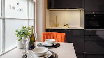 A modern kitchen with a black countertop, a gold faucet, and a white cabinet.