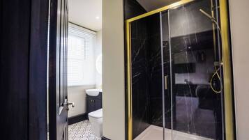 A bathroom with a toilet, sink, and a glass-enclosed shower area.
