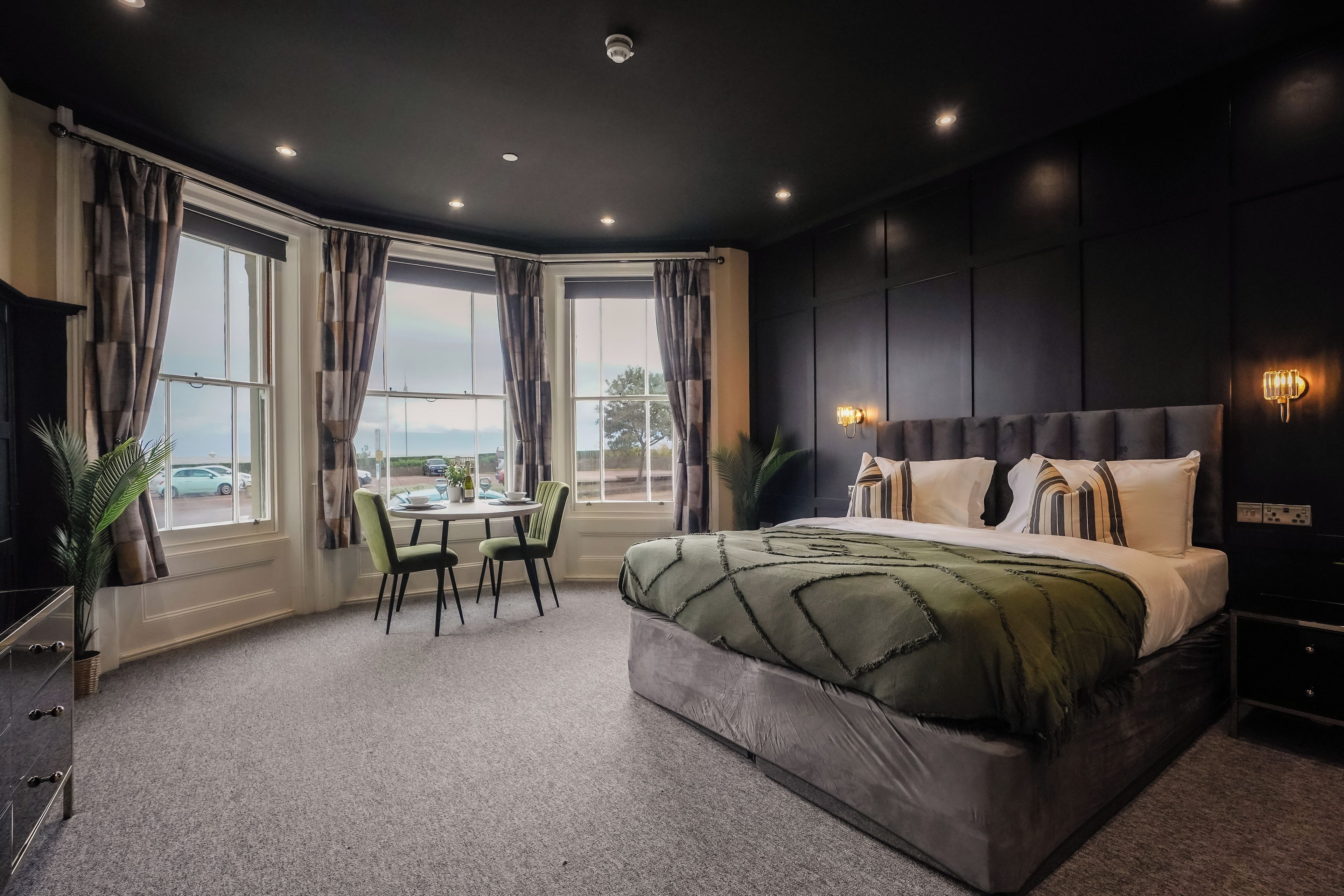 A modern bedroom with a large bed, a dining table, and chairs.