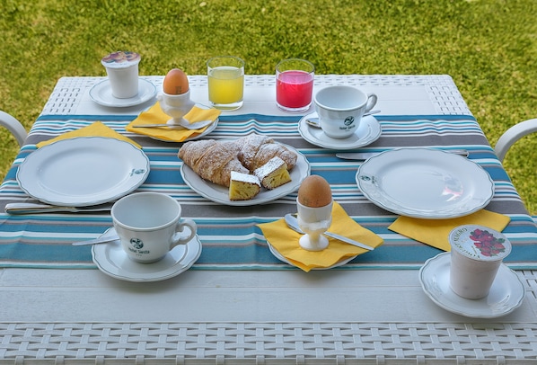 A table set for breakfast with plates, cups, and a pastry. - Hotel Siesta (Camaiore)