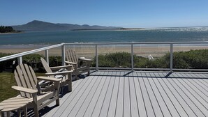 A deck with Adirondack chairs overlooking a beach and ocean. - Lovely Beachfront Home with Amazing Views! (Netarts)