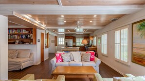 A spacious living area with a sofa set, a coffee table, and a bookshelf. - Green Shutters: Charming 19th-Century Cottage in the Heart of Hope Town (Elbow Cay)