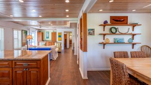 A spacious kitchen with wooden cabinets and a dining area with wicker chairs. - Green Shutters: Charming 19th-Century Cottage in the Heart of Hope Town (Elbow Cay)