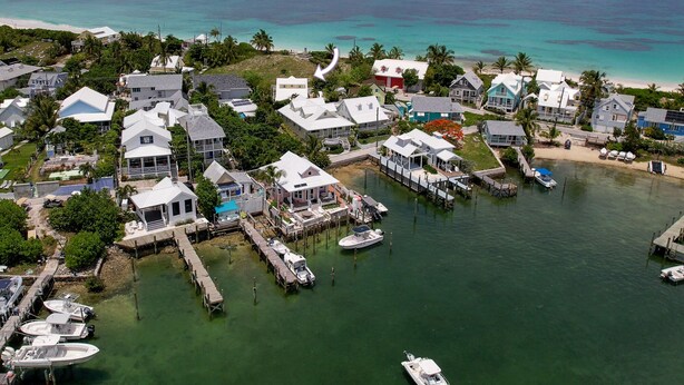 An aerial view of a coastal residential area with houses, docks, and boats. - Green Shutters: Charming 19th-Century Cottage in the Heart of Hope Town (Elbow Cay)
