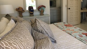 A bedroom with a bed, pillows, a dresser, a mirror, and a door leading to a bathroom. - Gentle Winds, St. Croix, U.S.V.I. - come unwind! (St. Croix)